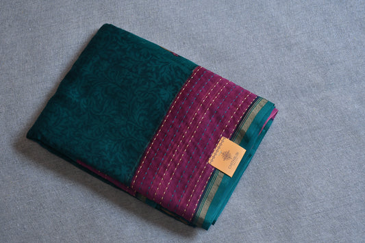 Folded fabric with green and purple pattern on a gray surface